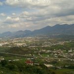 Panoramic view of a sprawling city nestled among rolling hills
